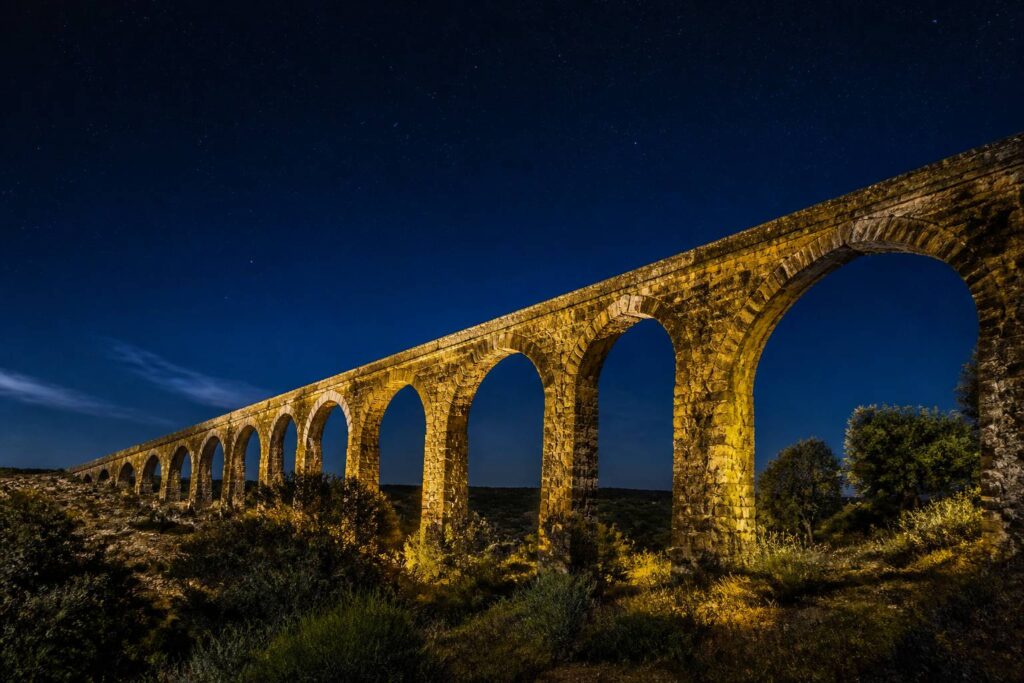 Aqueduc romain en pierre sous une lumière dorée dans un paysage méditerranéen